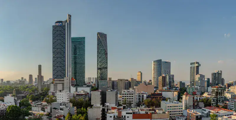 Panoramic view of Mexico City's skyline featuring Torre BBVA and Torre Reforma during sunset.