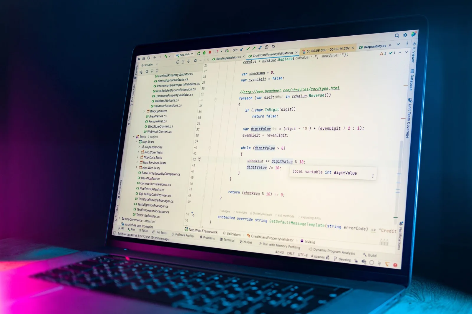 La pantalla de una computadora portátil muestra un editor de código con código de programación visible en un entorno con poca luz.