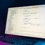 La pantalla de una computadora portátil muestra un editor de código con código de programación visible en un entorno con poca luz.