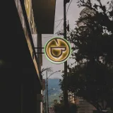 A glowing neon sign illuminates a quaint street in Mérida, Venezuela, at twilight.