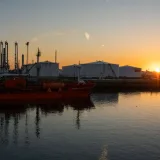 Una pintoresca vista de un puerto industrial y un buque cisterna al amanecer, que crean una silueta impresionante.
