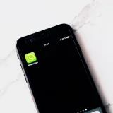 Imagen en primer plano de un teléfono inteligente que muestra WhatsApp sobre una mesa blanca.