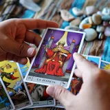 Manos sosteniendo una carta del tarot de la justicia sobre una tela colorida durante una lectura.