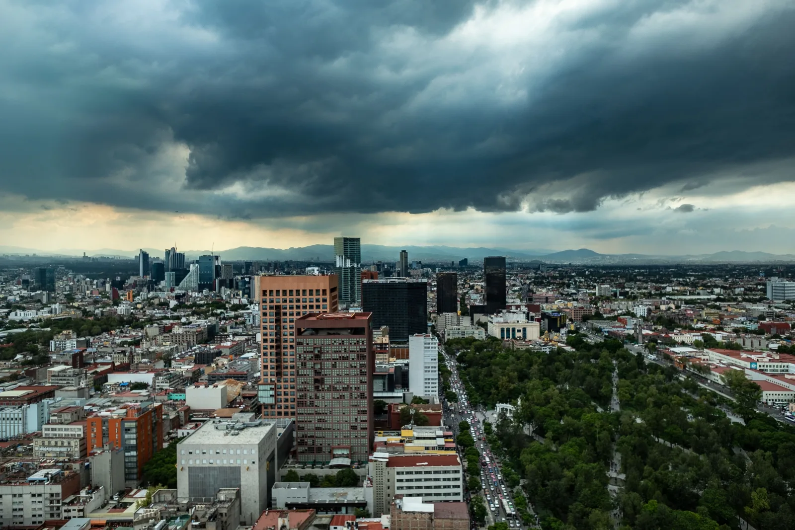 Vista aérea del horizonte de Ciudad de México bajo oscuras nubes de tormenta, que muestra la arquitectura urbana y un clima dramático.