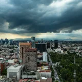 Vista aérea del horizonte de Ciudad de México bajo oscuras nubes de tormenta, que muestra la arquitectura urbana y un clima dramático.