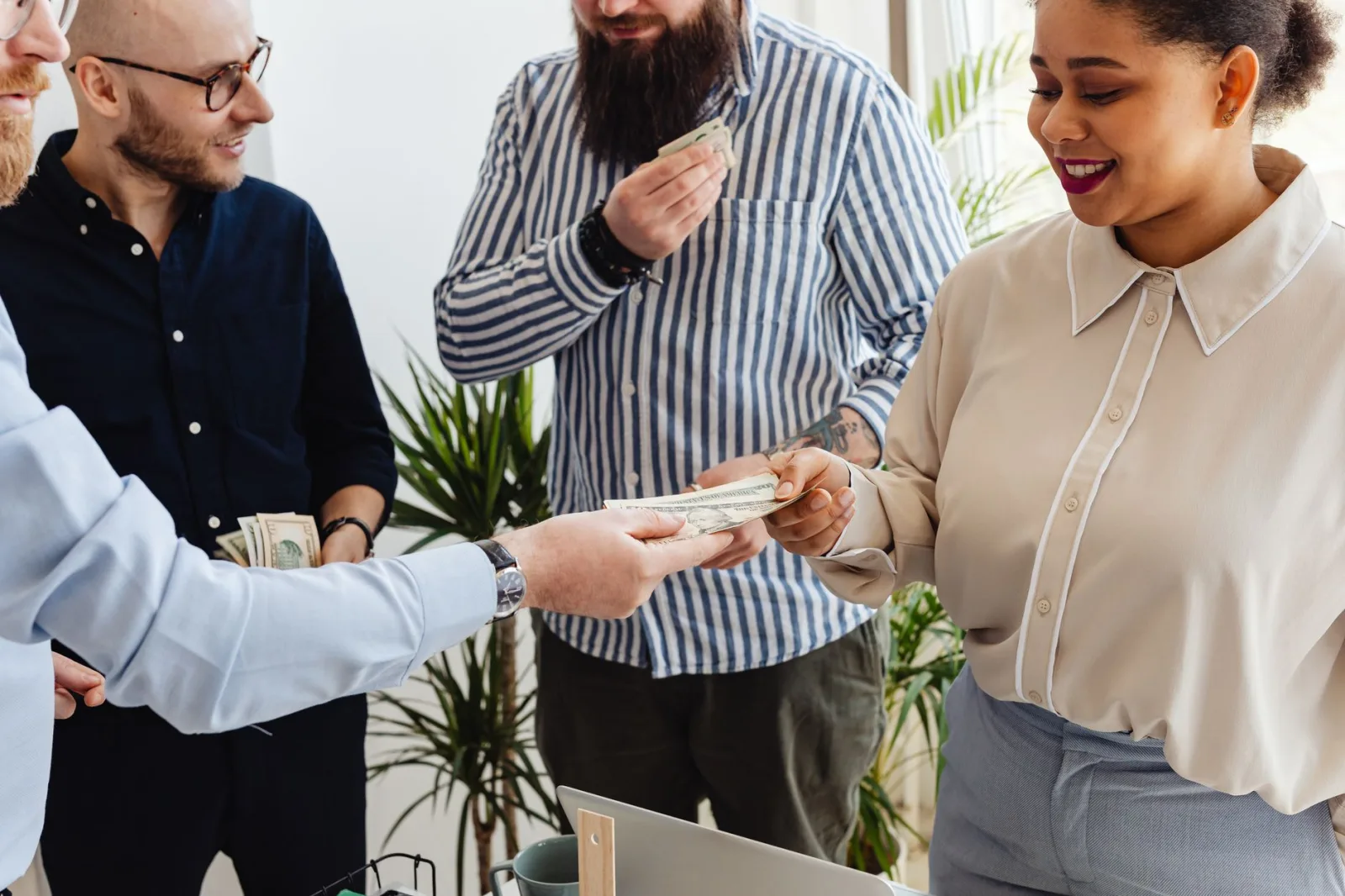 Profesionales de negocios intercambiando dinero en un ambiente de oficina informal.