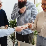 Profesionales de negocios intercambiando dinero en un ambiente de oficina informal.