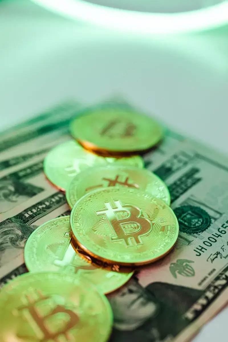 Golden Bitcoin coins placed over American dollar banknotes, highlighting crypto and cash economy.