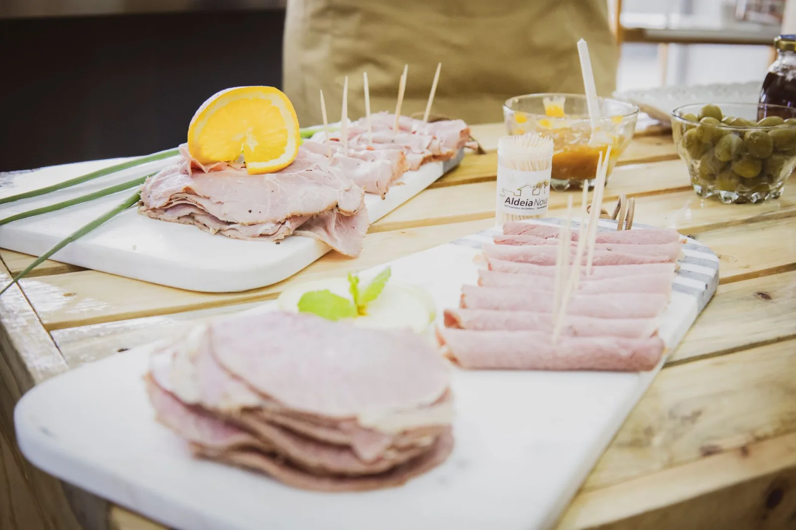 Deliciosos aperitivos de jamón en lonchas, adornados con naranja y servidos en bandejas de madera.