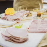 Deliciosos aperitivos de jamón en lonchas, adornados con naranja y servidos en bandejas de madera.