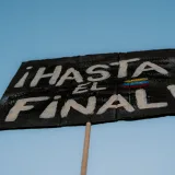 Close-up of a protest sign saying "Hasta el Final" against a clear blue sky.