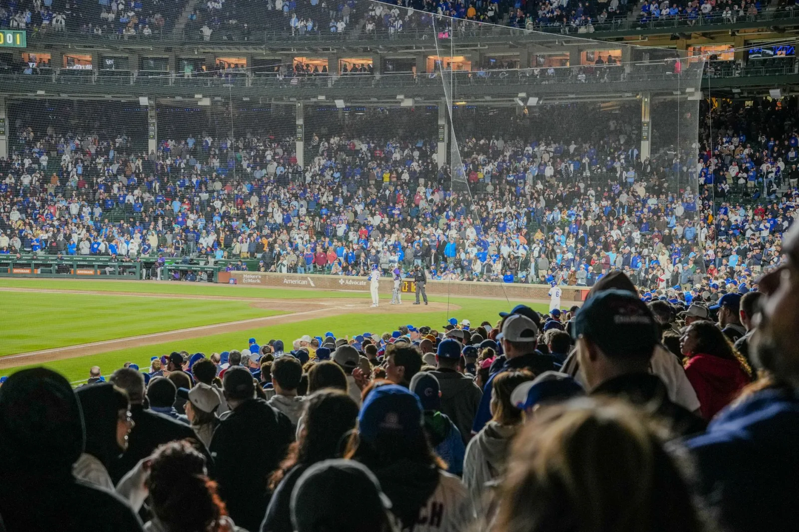 Escena llena de energía de un partido de béisbol nocturno con un estadio repleto de público.