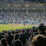Escena llena de energía de un partido de béisbol nocturno con un estadio repleto de público.