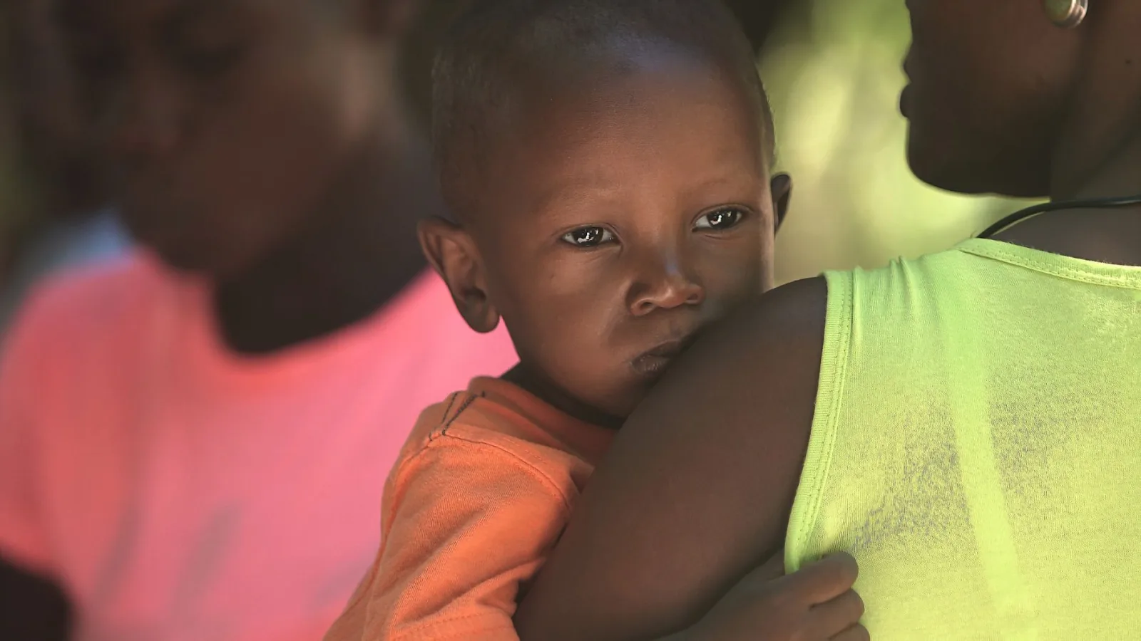 Primer plano de una madre que lleva a su hijo en brazos, capturando un momento tierno en Haití.