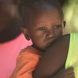 Primer plano de una madre que lleva a su hijo en brazos, capturando un momento tierno en Haití.