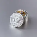 Close-up of shiny Bitcoin cryptocurrency coins with a reflective surface on a gray background.