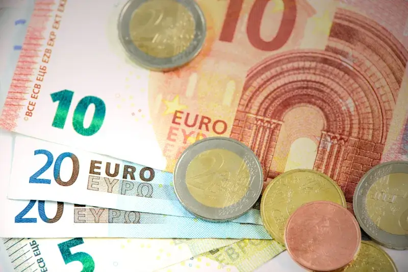 Detailed shot of Euro banknotes and coins showcasing currency denominations.