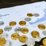 Gold and silver Bitcoin coins placed on a graph showing LocalBitcoins trading volume analysis, symbolizing cryptocurrency market trends.