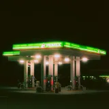 Gasolinera Pemex iluminada con luces verdes brillantes contra el cielo nocturno, resaltando el tema de viaje