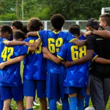Un vibrante momento de unión mientras un equipo juvenil de fútbol se reúne en un estadio de Caracas.