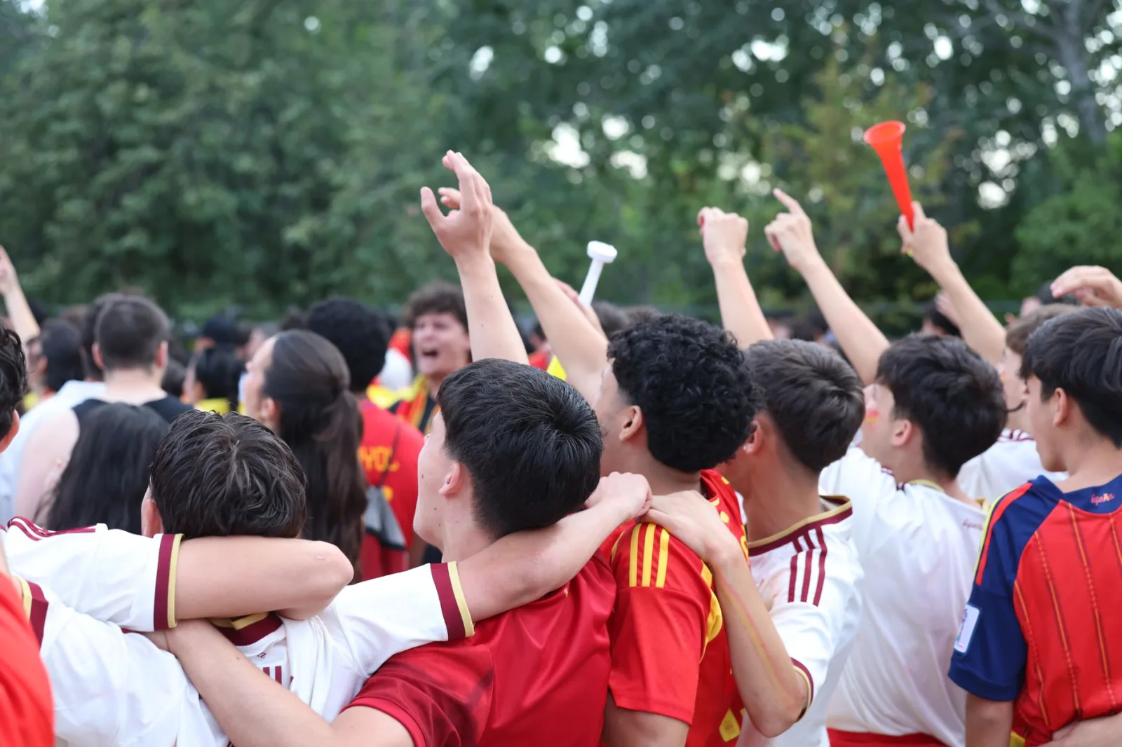 Aficionados emocionados celebran en un evento deportivo al aire libre en Madrid, expresando alegría y unidad.