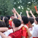 Aficionados emocionados celebran en un evento deportivo al aire libre en Madrid, expresando alegría y unidad.