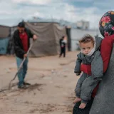 Una escena conmovedora de una madre y su hijo en un campamento de refugiados en Gaza, que destaca la resiliencia.