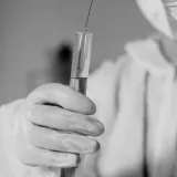 Científico con equipo de protección trabajando con un tubo de ensayo en un laboratorio.