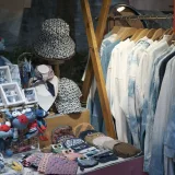 Un puesto colorido que exhibe artesanías y ropa hechas a mano, dispuestas ordenadamente.