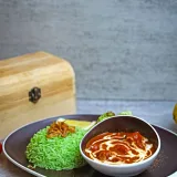 Un plato de arroz verde lleno de sabor, servido con un curry picante y guarniciones, ideal para fotografía gastronómica.