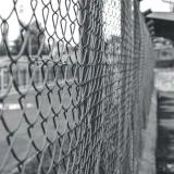 Imagen en blanco y negro de una valla de malla metálica en una zona urbana de Marruecos.