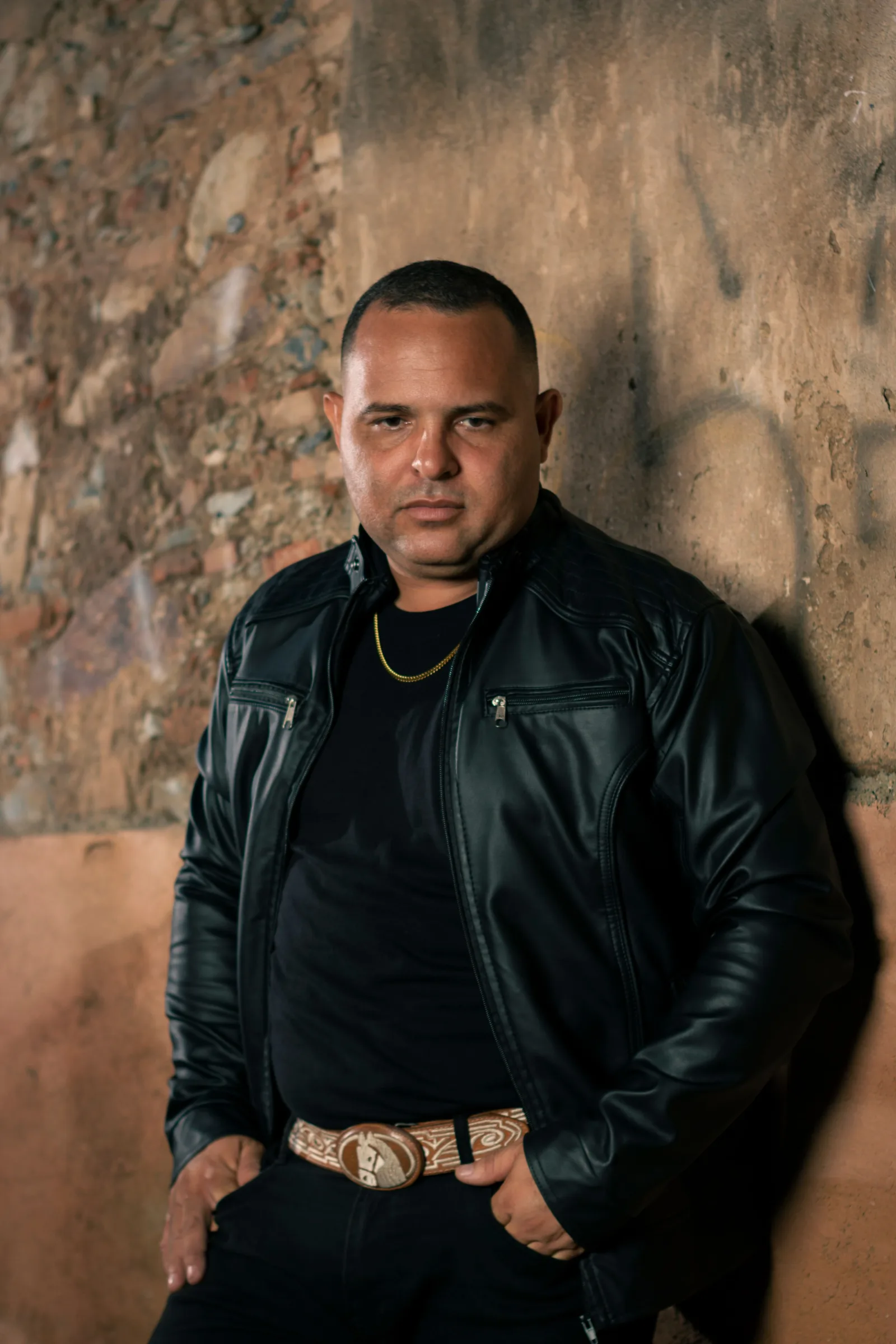 Man with leather jacket standing against a rustic wall in Guama, Venezuela.
