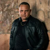 Man with leather jacket standing against a rustic wall in Guama, Venezuela.