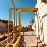 Tubería de gas amarilla bajo un cielo azul despejado en una fábrica de cemento de Arabia Saudita.