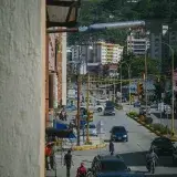 Animada calle urbana en Venezuela que muestra la vida cotidiana de la ciudad, con automóviles y peatones.