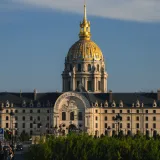 La majestuosa cúpula de Los Inválidos, en París, Francia, iluminada por la luz del día bajo un cielo azul.