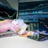 Dinero y finanzas. Pantallas de oficina con gráficos bursátiles. Billete de euro.