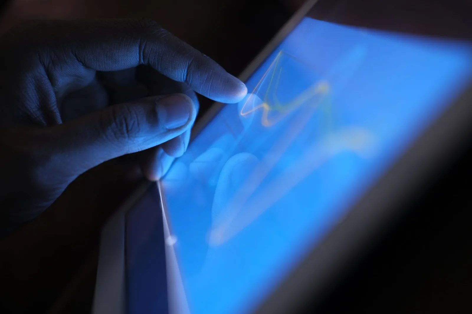 Primer plano de una mano interactuando con la pantalla táctil de una tableta, mostrando el uso de tecnología moderna.