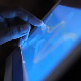 Primer plano de una mano interactuando con la pantalla táctil de una tableta, mostrando el uso de tecnología moderna.