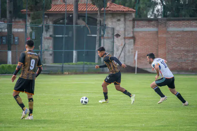 Dynamic action shot of soccer players competing on a grassy field in Texcoco, México.
