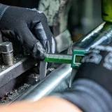 Primer plano de un mecánico utilizando un micrómetro en una máquina, destacando la precisión en la ingeniería.