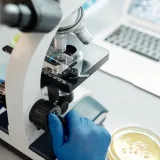 Investigador analizando muestras biológicas bajo un microscopio en un laboratorio.