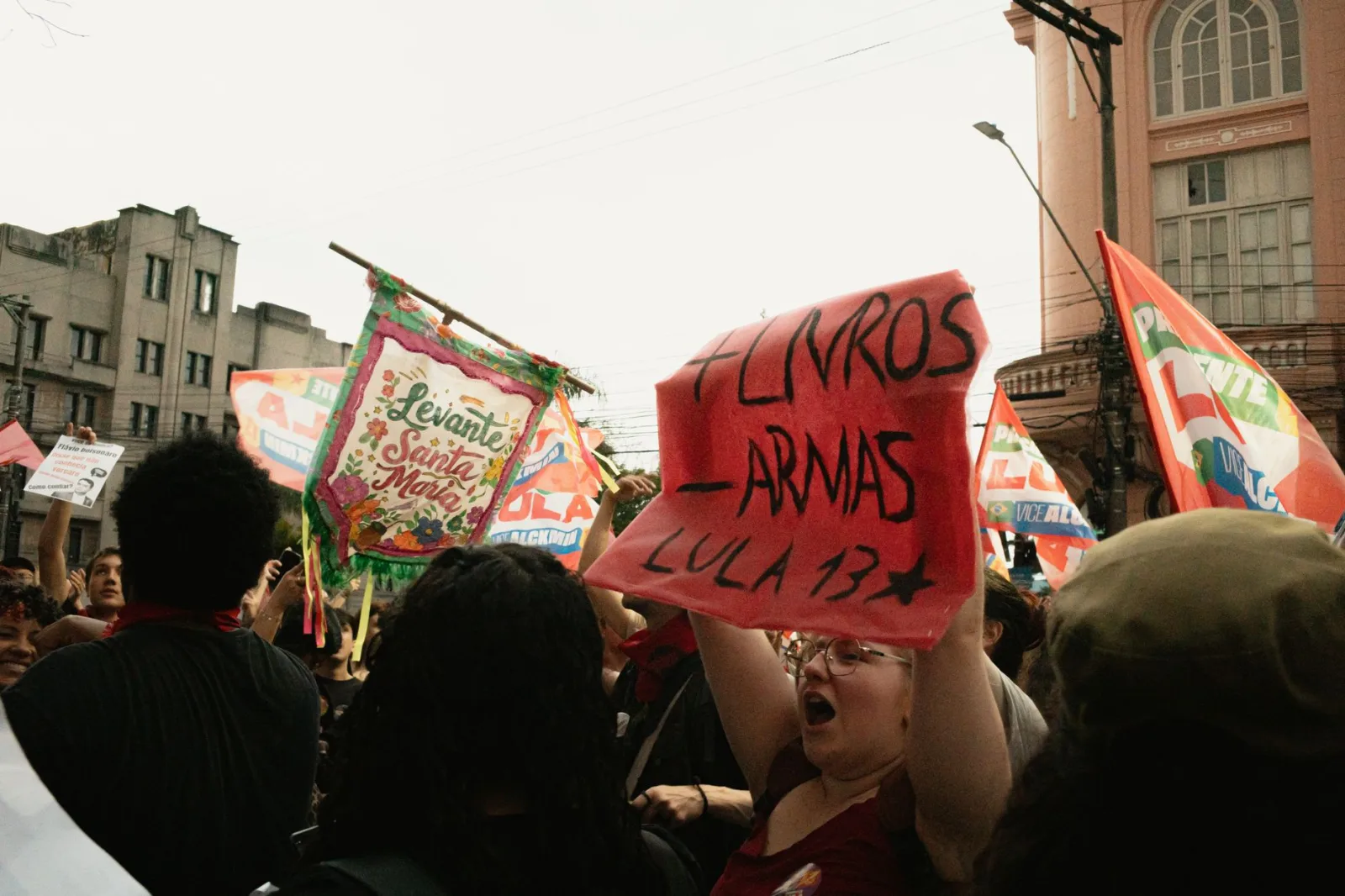 Manifestantes sostienen pancartas y carteles durante una concentración política en una calle urbana.