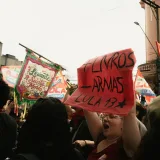 Manifestantes sostienen pancartas y carteles durante una concentración política en una calle urbana.