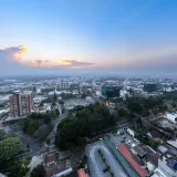 Panoramic aerial view of Guatemala City during sunset, showcasing urban landscape and skyline.