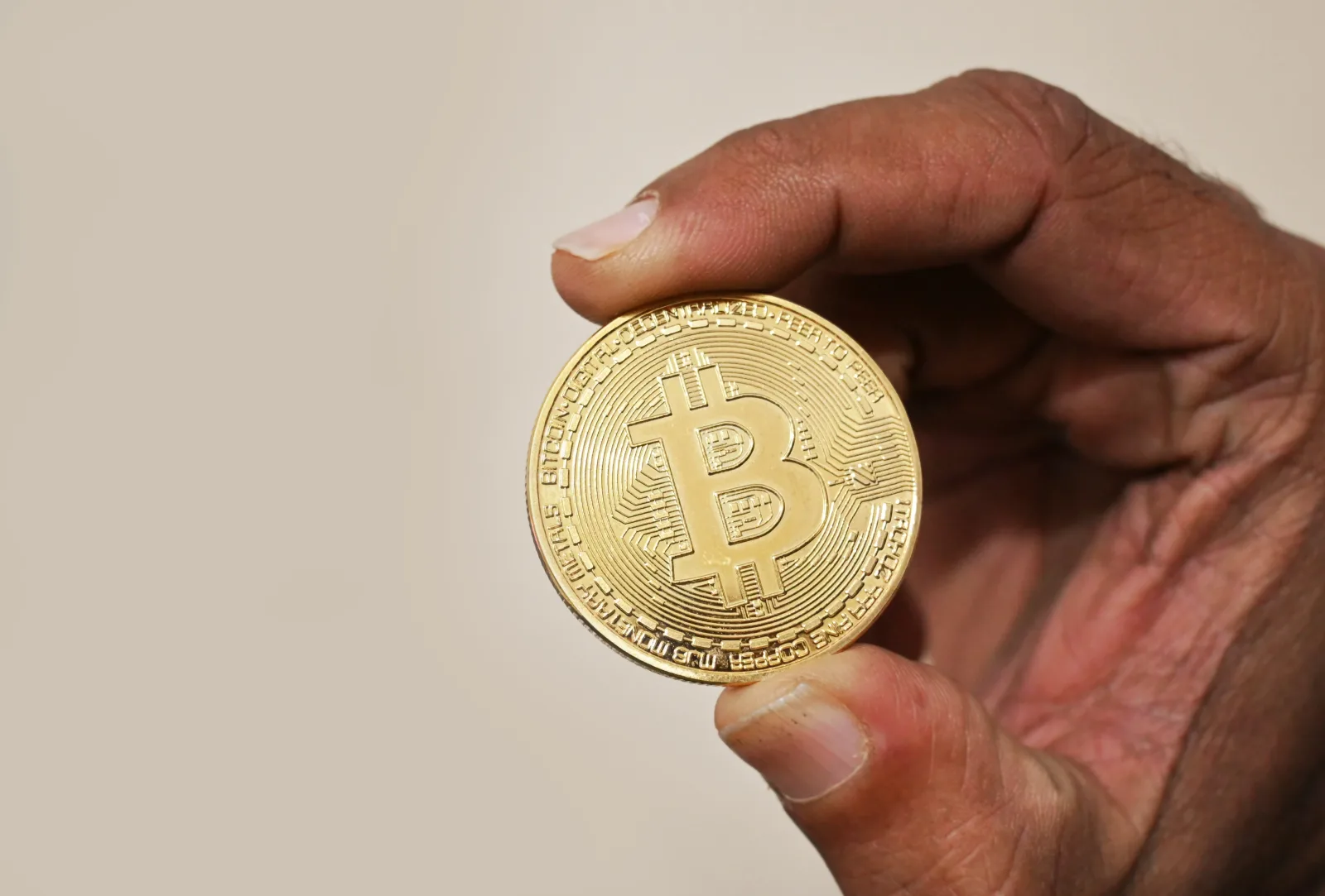 Sosteniendo una moneda de Bitcoin, la criptomoneda