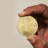 Sosteniendo una moneda de Bitcoin, la criptomoneda