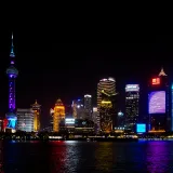 Vibrante panorama nocturno de Shanghai, con sus emblemáticos rascacielos y coloridas reflejos de luces en el agua.