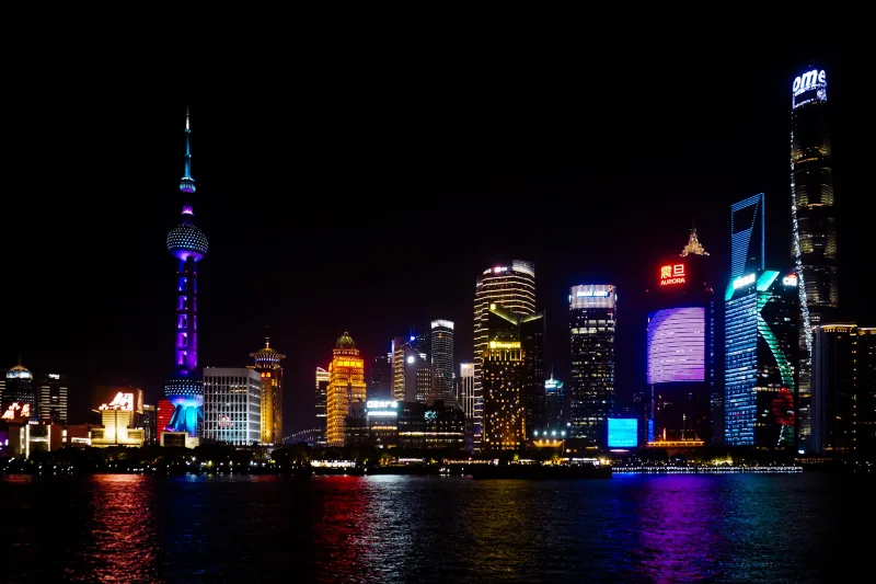 Vibrante panorama nocturno de Shanghai, con sus emblemáticos rascacielos y coloridas reflejos de luces en el agua.