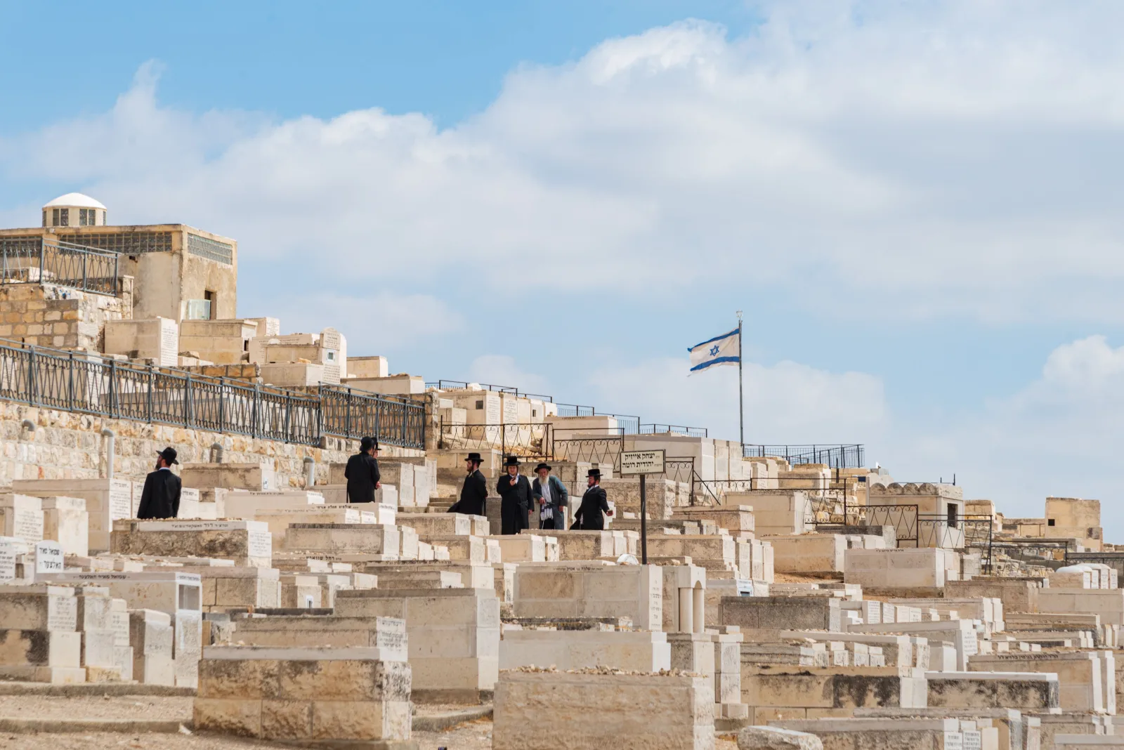 Hombres judíos ortodoxos se reúnen en el cementerio del Monte de los Olivos, en Jerusalén, Israel, bajo un cielo despejado.